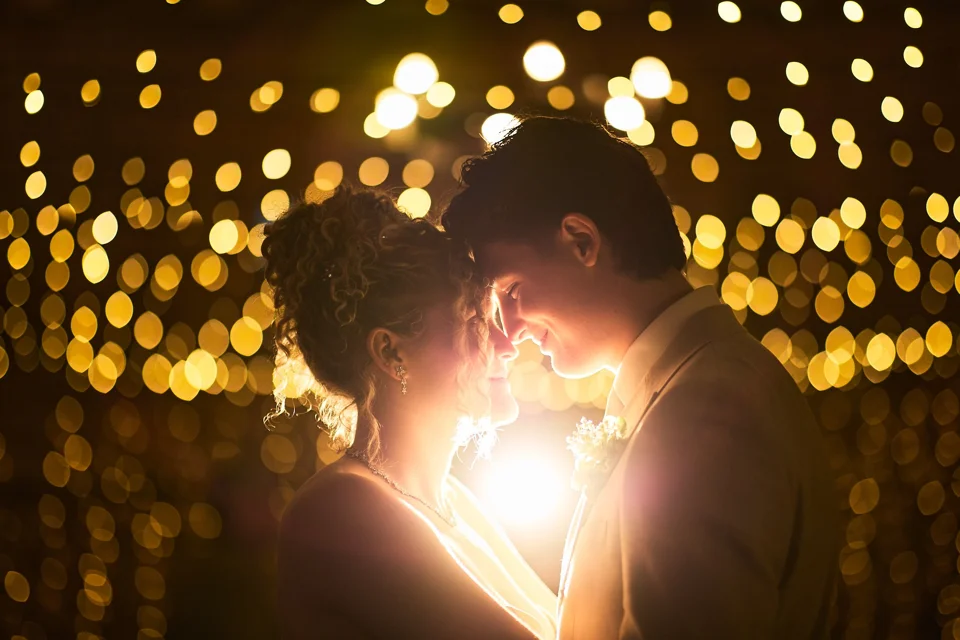 The couple kissing beneath fairy lights at night