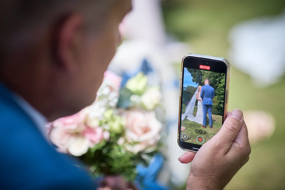 A wedding guest taking a photograph on a phone